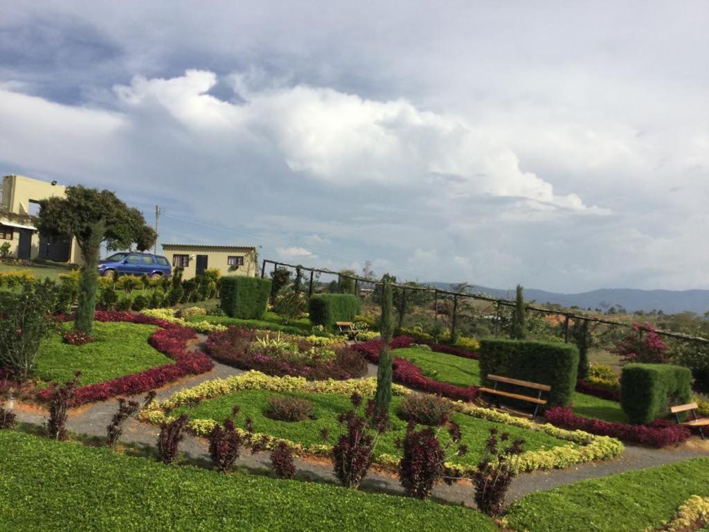 a park with a garden with flowers and a bench at Casas La Colina in Curití