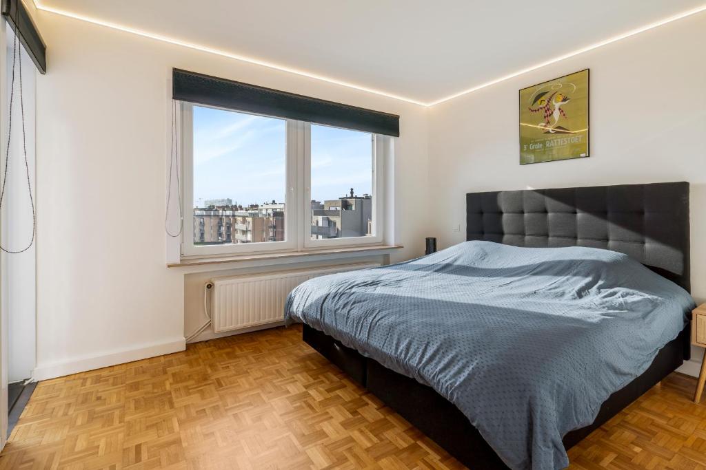 ein Schlafzimmer mit einem Bett und einem großen Fenster in der Unterkunft Fantastically located modern apartment with garage available in Ostende