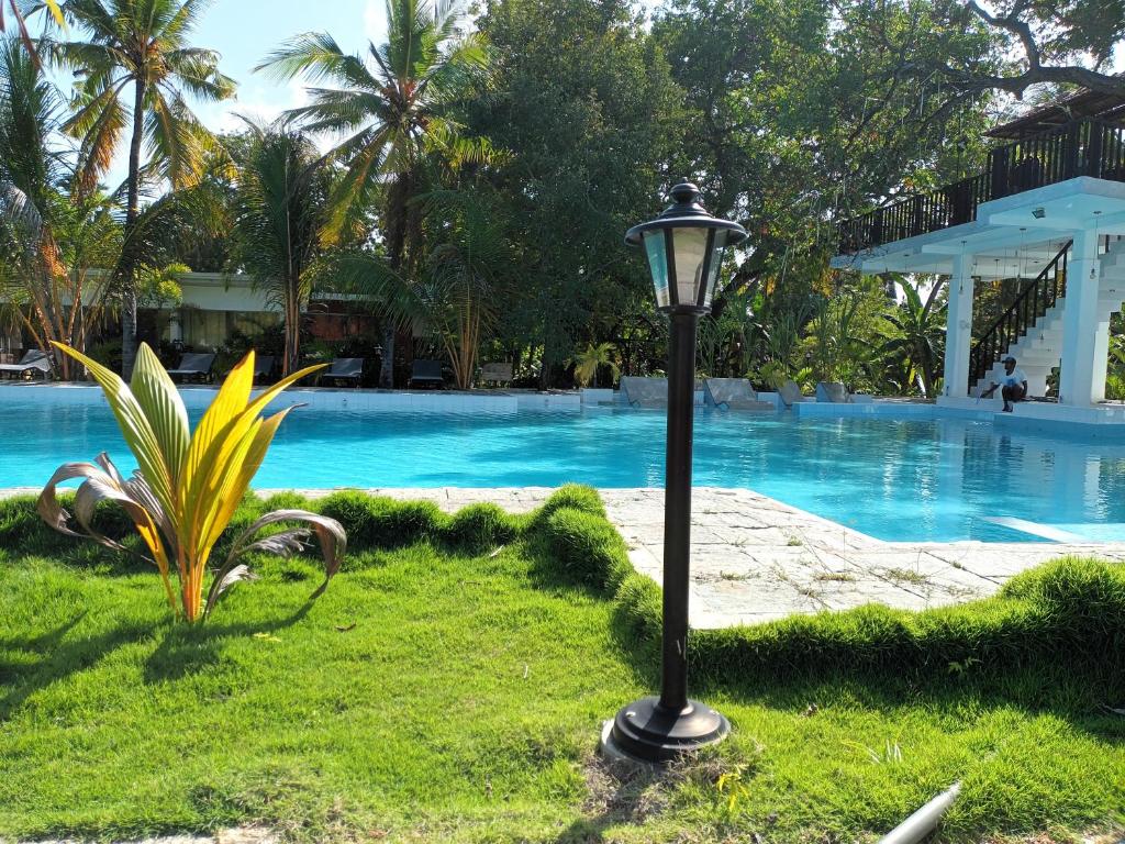 a lamp in the grass next to a swimming pool at Lucky Beach Resort in Trincomalee
