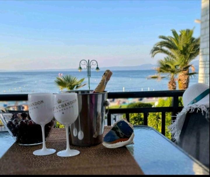 stół z 2 kieliszkami do wina na balkonie z widokiem na ocean w obiekcie Cozy maisonette in Pefkochori Chalkidiki w mieście Pefkochori