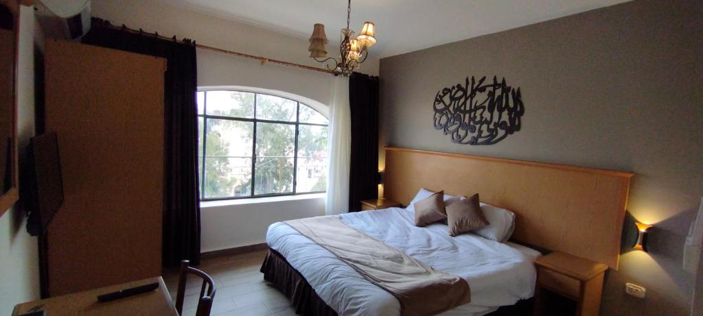 a bedroom with a bed with a large window at Moab Hotel & Restaurant in Madaba