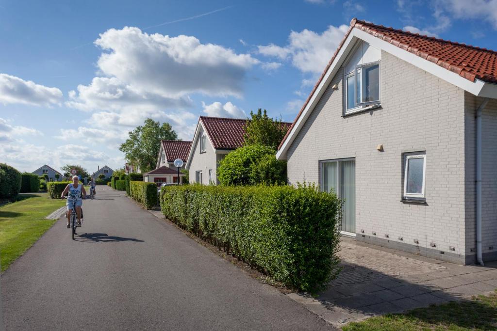 uma pessoa a andar de bicicleta numa estrada ao lado de uma casa em Noordwijk Holiday Rentals em Noordwijk