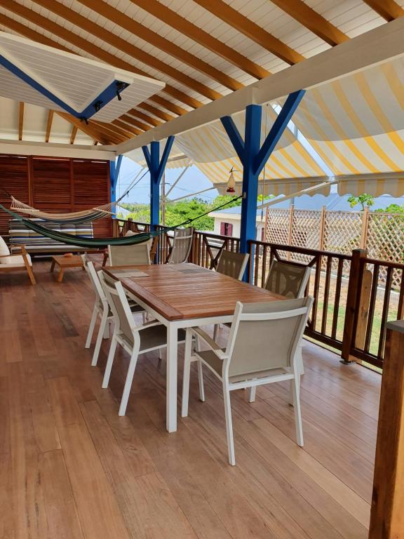 a wooden table and chairs on a deck with a hammock at Chambre chez l'habitant à L' Amirade chez Michelle in Grande Anse