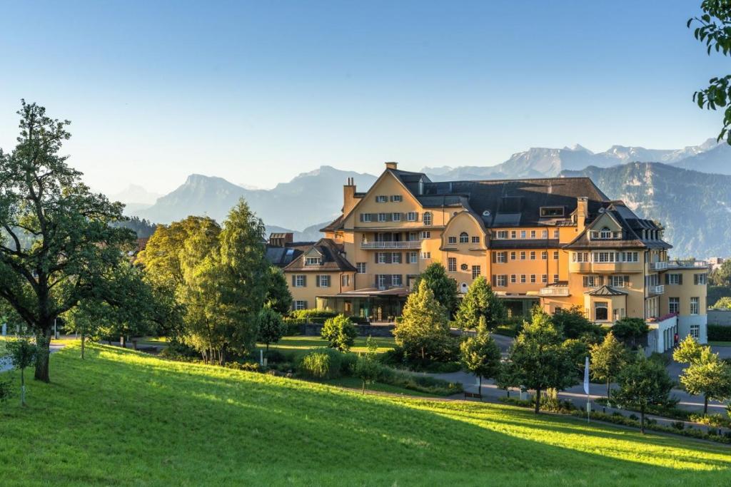 ein großes Haus auf einem Hügel mit grünem Feld in der Unterkunft Kurhotel Sonnmatt Luzern in Luzern