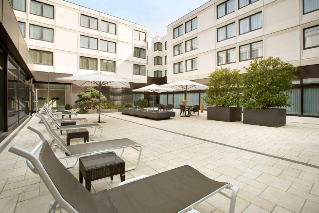 een patio met tafels en stoelen voor een gebouw bij Ramada Nürnberg Parkhotel in Neurenberg