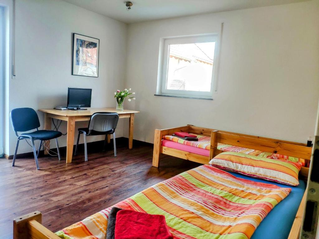 a bedroom with a bed and a desk with a computer at Ruhiges Zimmer am Tuniberg Freiburg in Freiburg im Breisgau