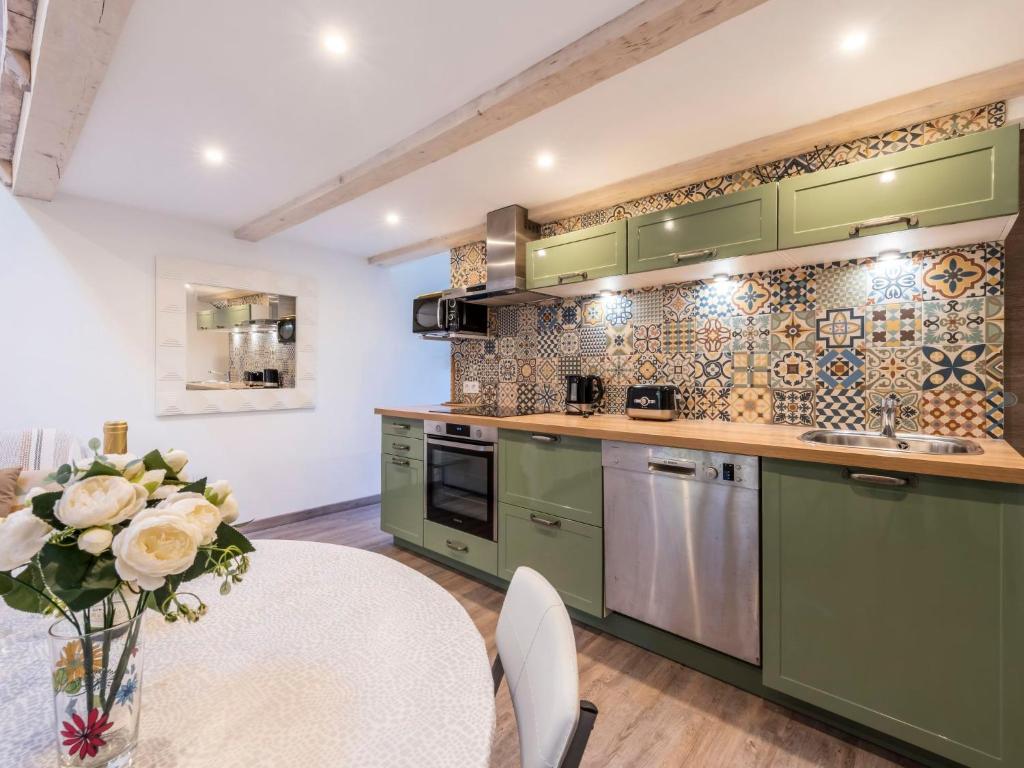 a kitchen with green cabinets and a table with a vase of flowers at Apartment Gigaro Plage by Interhome in La Croix-Valmer