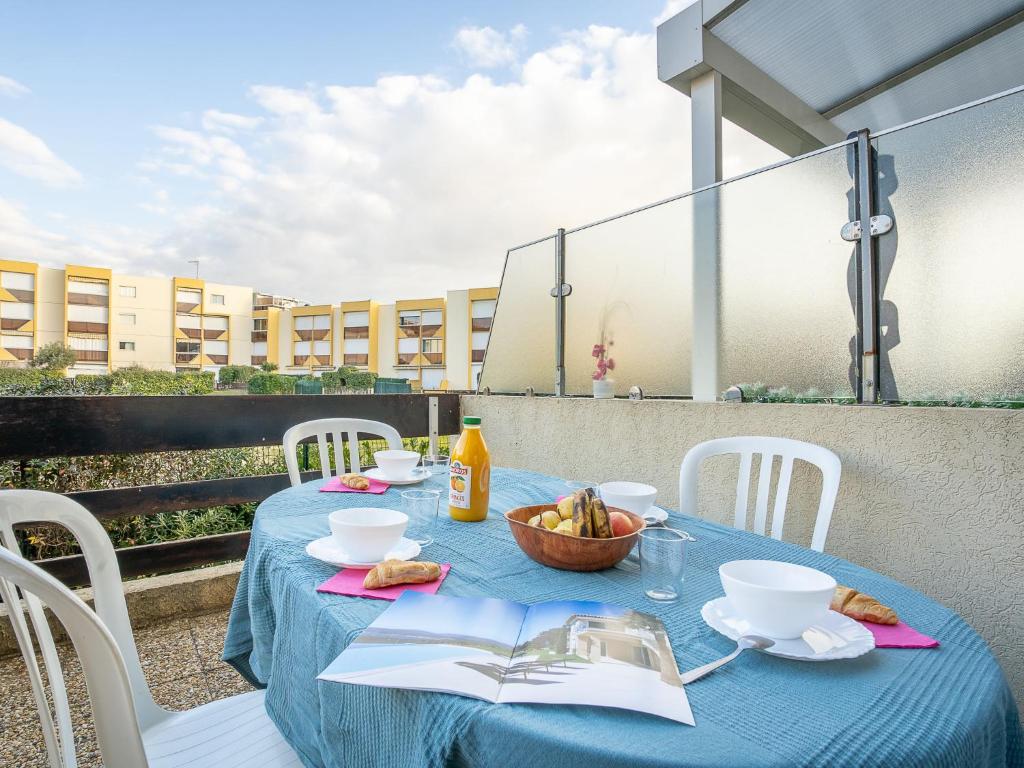 une table bleue avec un bol de fruits et un livre dans l'établissement Apartment Los Amigos-4 by Interhome, au Grau-du-Roi