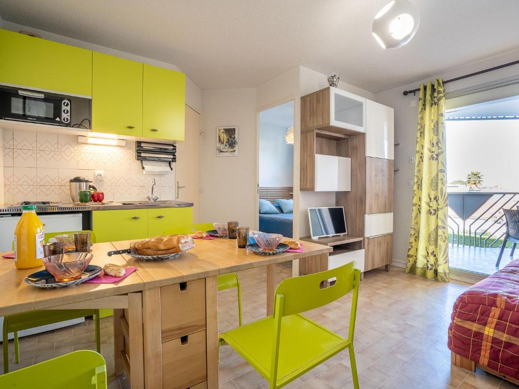 a kitchen with yellow cabinets and a table and chairs at Apartment Les Caraïbes-1 by Interhome in Le Grau-du-Roi