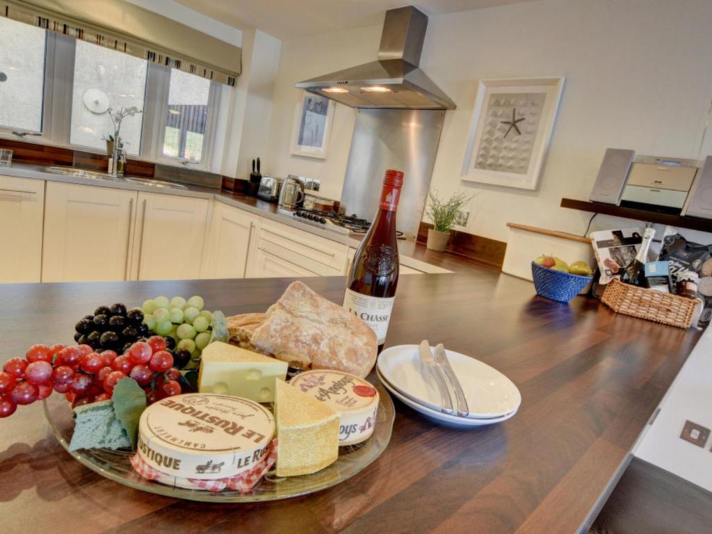 a table with a bottle of wine and a plate of cheese at Apartment Rockham by Interhome in Mortehoe