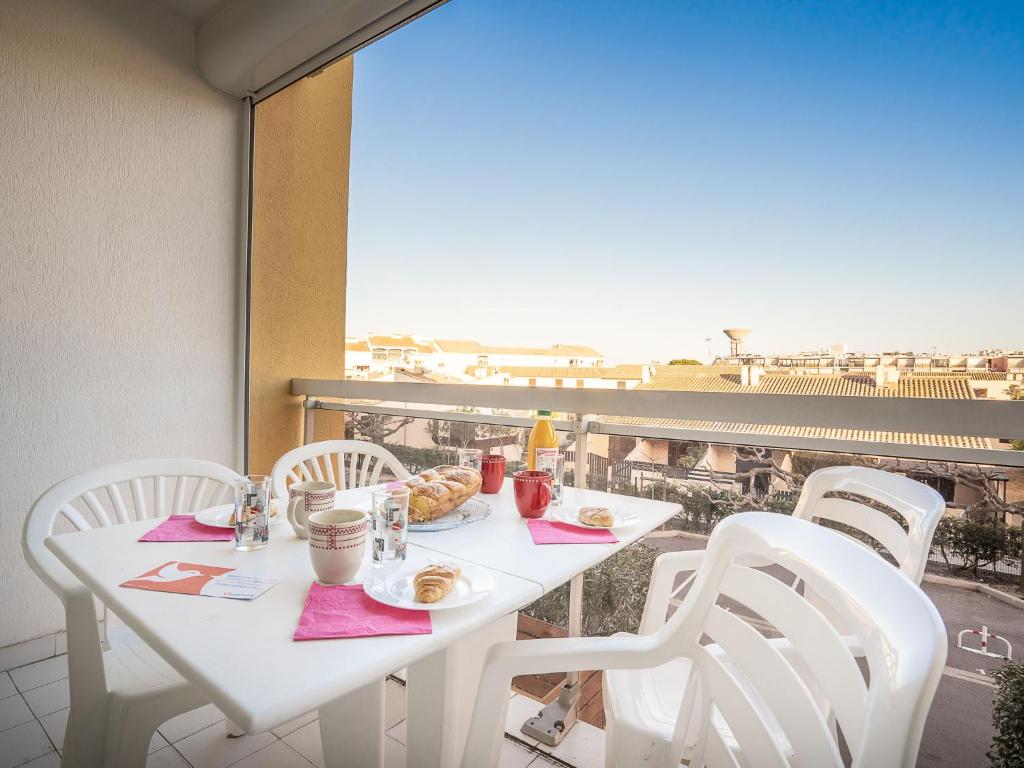 a white table with breakfast food on a balcony at Studio Voiles d'Or-Gênois-3 by Interhome in Le Grau-du-Roi