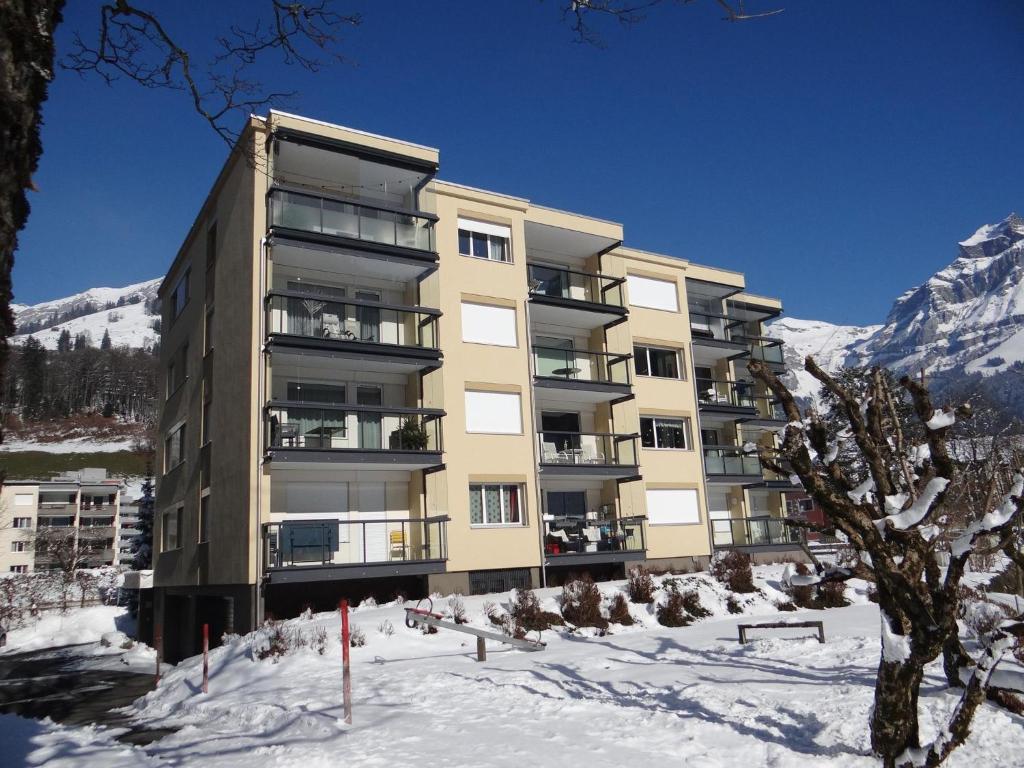 um edifício na neve com montanhas ao fundo em Apartment Erlenrain Wohnung 722E by Interhome em Engelberg