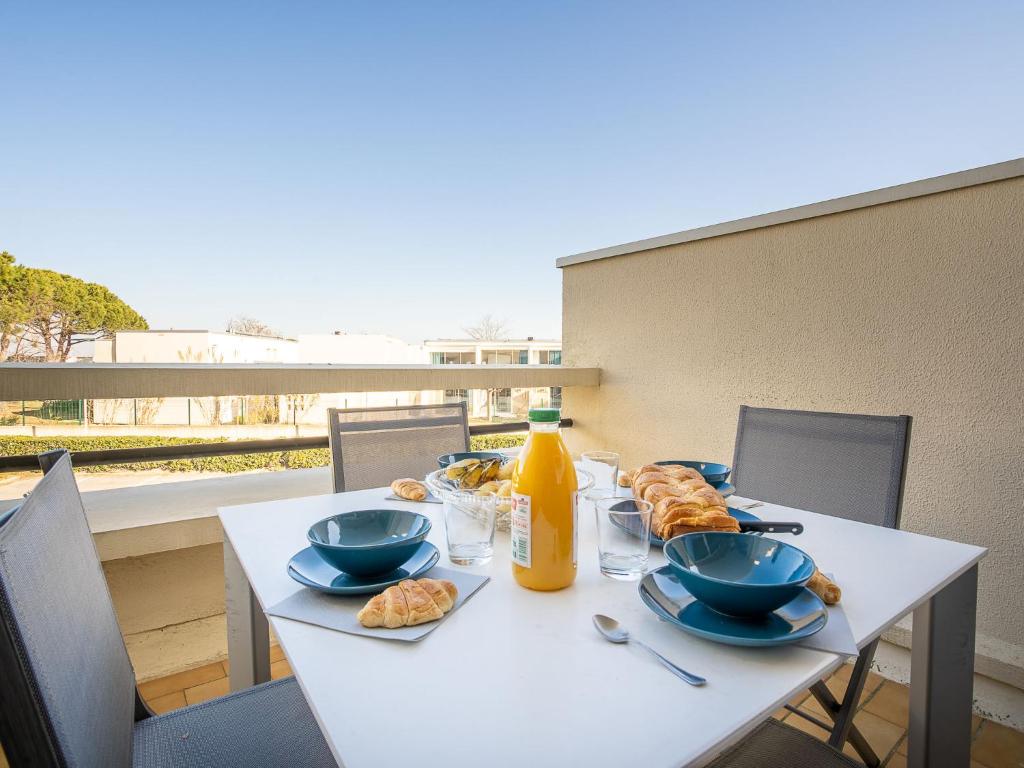 une table blanche avec des assiettes de nourriture et de jus d'orange dans l'établissement Apartment Le Serpent de Mer-7 by Interhome, au Grau-du-Roi