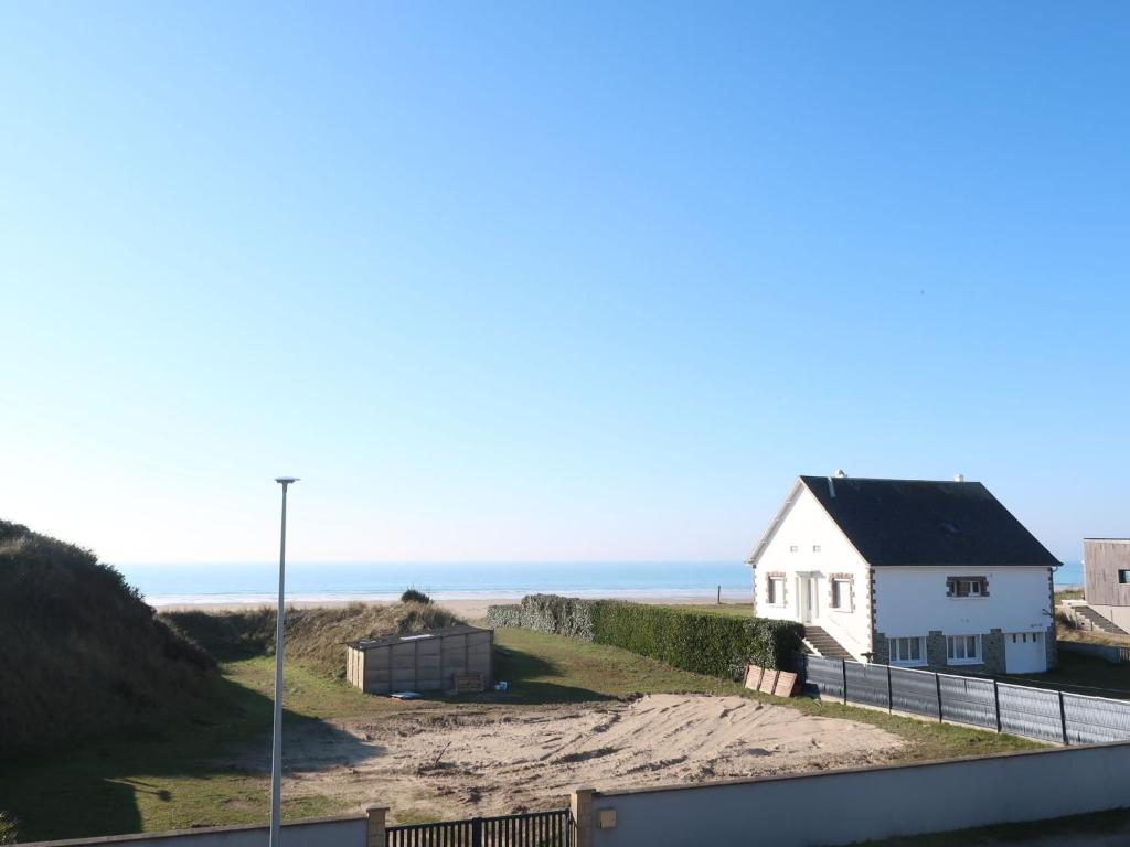 a house on the beach with the ocean in the background at Holiday Home La Plage by Interhome in Denneville