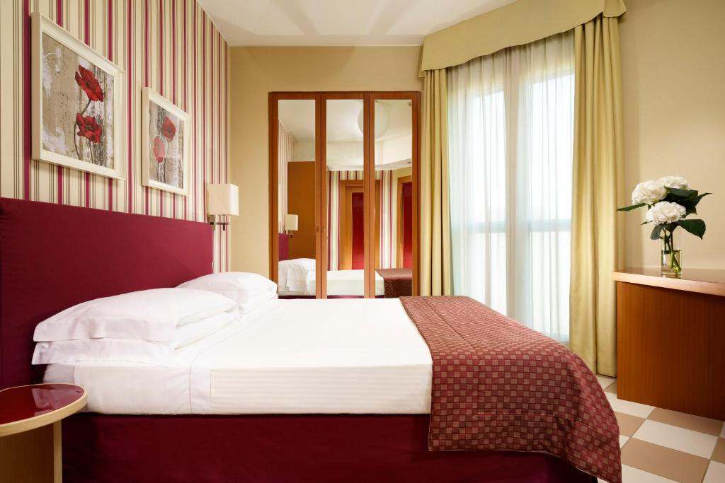 サン・ドナート・ミラネーゼにあるUNAHOTELS The ONE Milano Hotel & Residenceのベッドルーム1室(ベッド1台、大きな窓付)