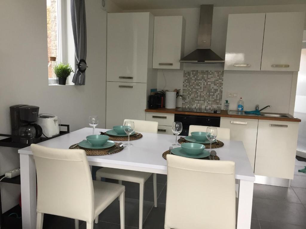 une cuisine équipée d'une table blanche avec des chaises et d'un astérisque dans l'établissement Les terrasses de Malmedy duplex 420, à Malmedy