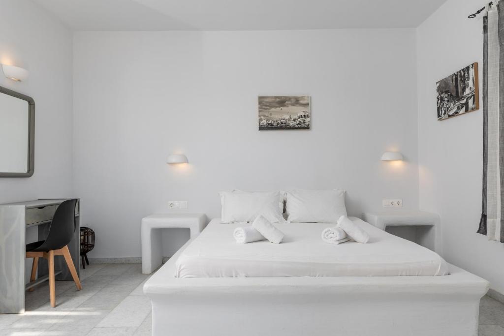 Habitación blanca con cama y escritorio en Helios Beach Studios, en Plaka