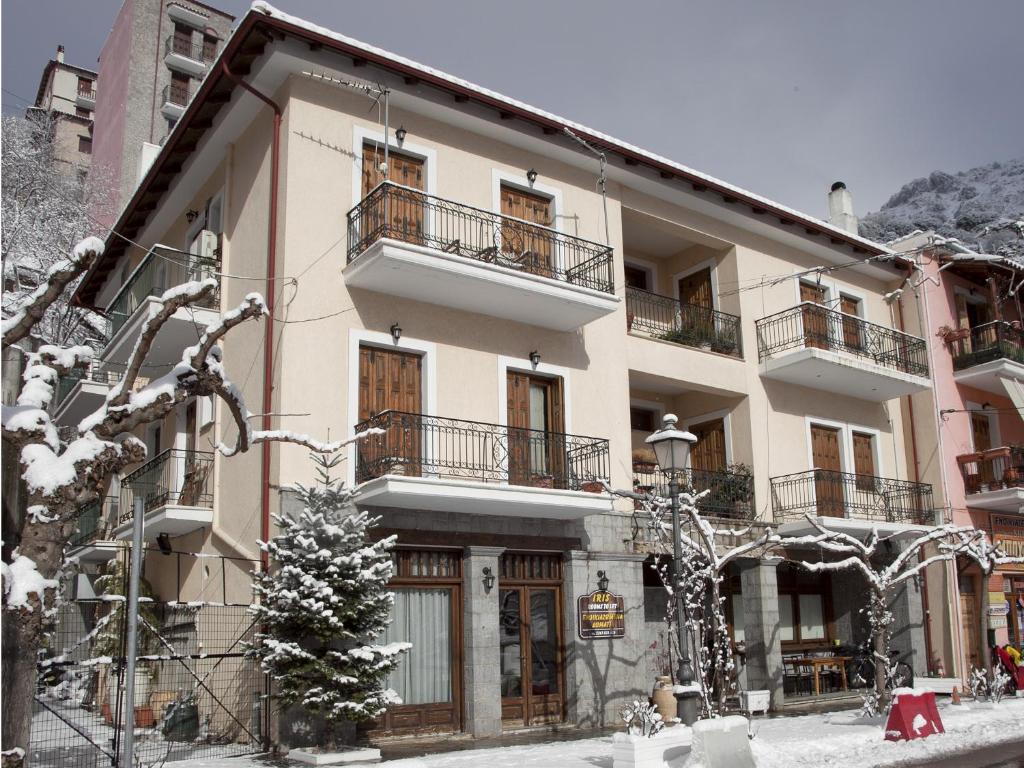 a large building with balconies on a snowy street at Iris in Arachova