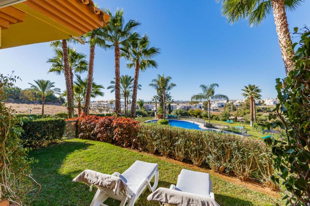 un par de sillas y una piscina con palmeras en Cumbres del Rodeo, en Marbella