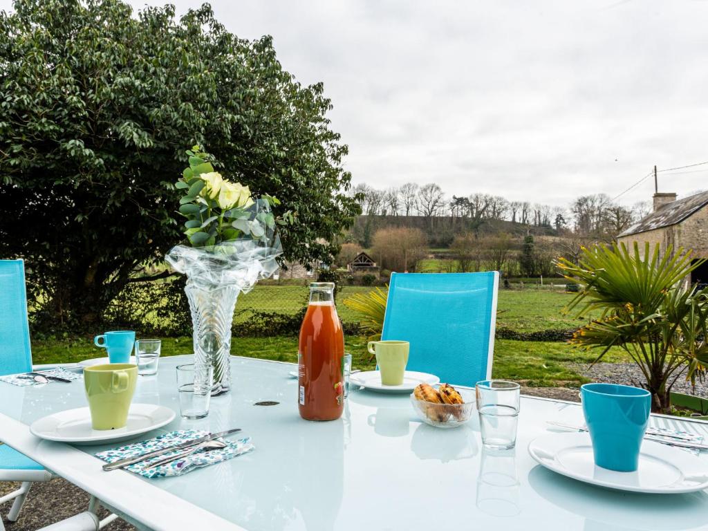 a white table with a vase of flowers and drinks at Holiday Home Le Clos Renard by Interhome in Commes