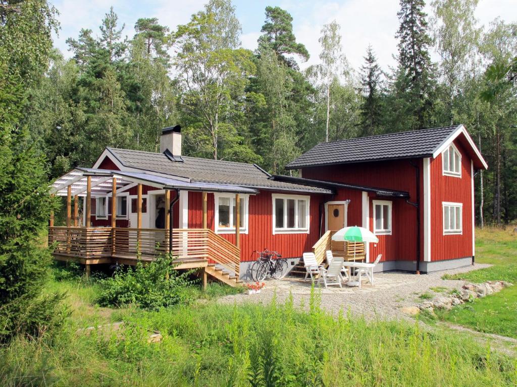 una cabaña roja en medio de un bosque en Chalet Lindby Karneolen - STH151 by Interhome, en Adelsö