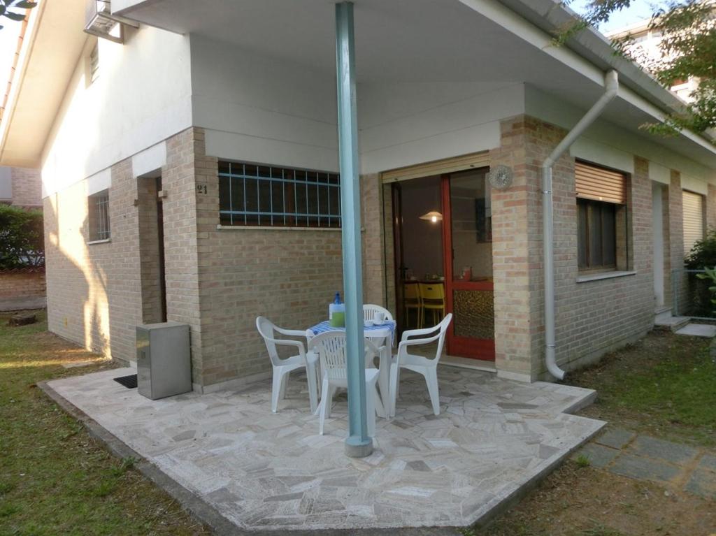 um pátio com uma mesa e cadeiras em frente a uma casa em Three-Bedroom Villa with garden, parking and ac em Bibione
