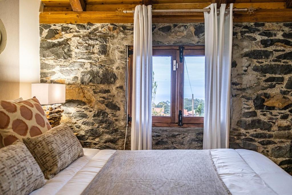 ein Schlafzimmer mit einem Bett mit einer Steinwand in der Unterkunft King Shelter by Homie in Lanceiros