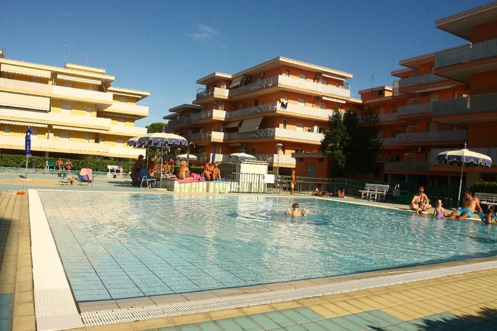 a swimming pool with people sitting in the water at Nice apartment in a residence with swimming pool in Bibione