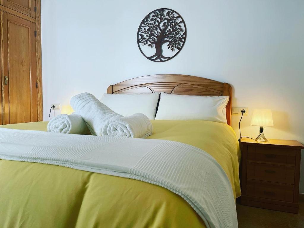 a bedroom with a yellow bed with a tree on the wall at APARTAMENTOs PONDOS in Linares
