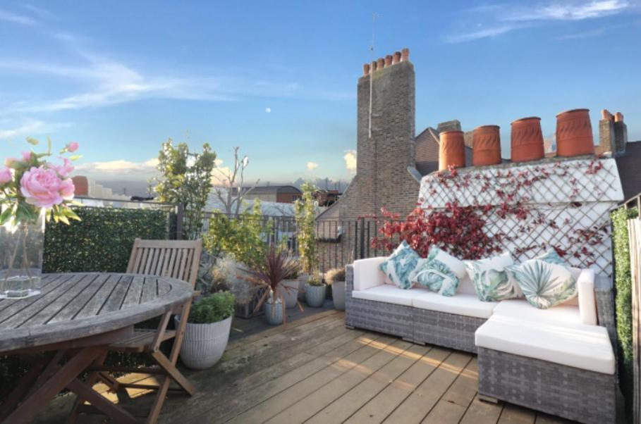 patio z kanapą i stołem oraz roślinami w obiekcie Highgate Maisonette with Roof Terrace w Londynie