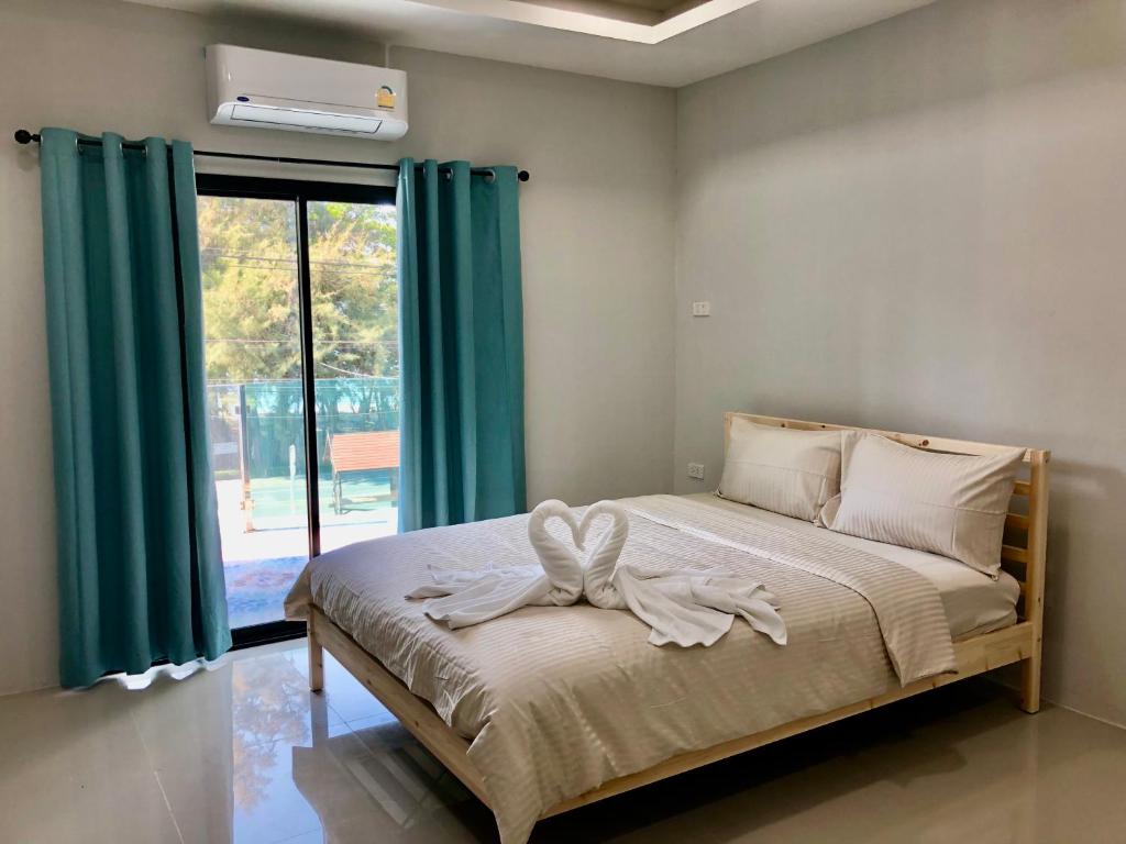 uma cama num quarto com cortinas verdes e uma janela em Emma em Ban Pak Khlong Phe