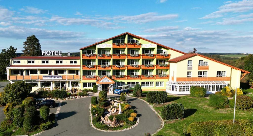 an aerial view of a hotel with a parking lot at Meister BÄR HOTEL Frankenwald in Berg