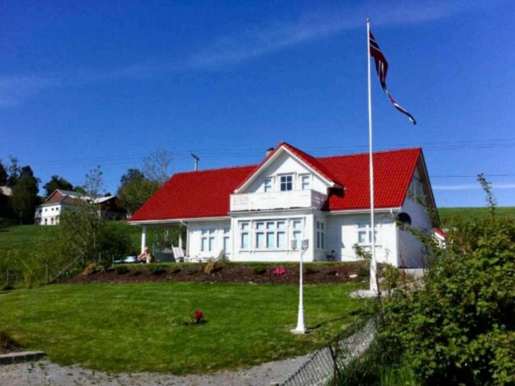 a white house with a red roof and a flag at Holiday home Sæbøvik in Sæbøvik