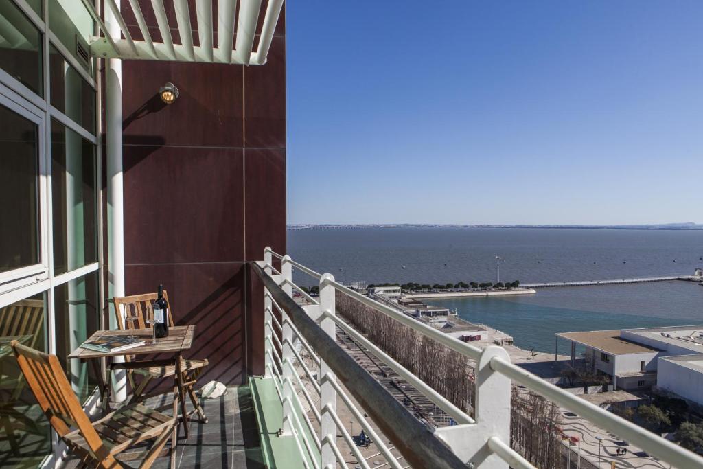uma varanda com cadeiras e uma mesa e o oceano em RENT4REST LISBON PARQUE DAS NAÇÕES 17Th FLOOR RIVER VIEW em Lisboa