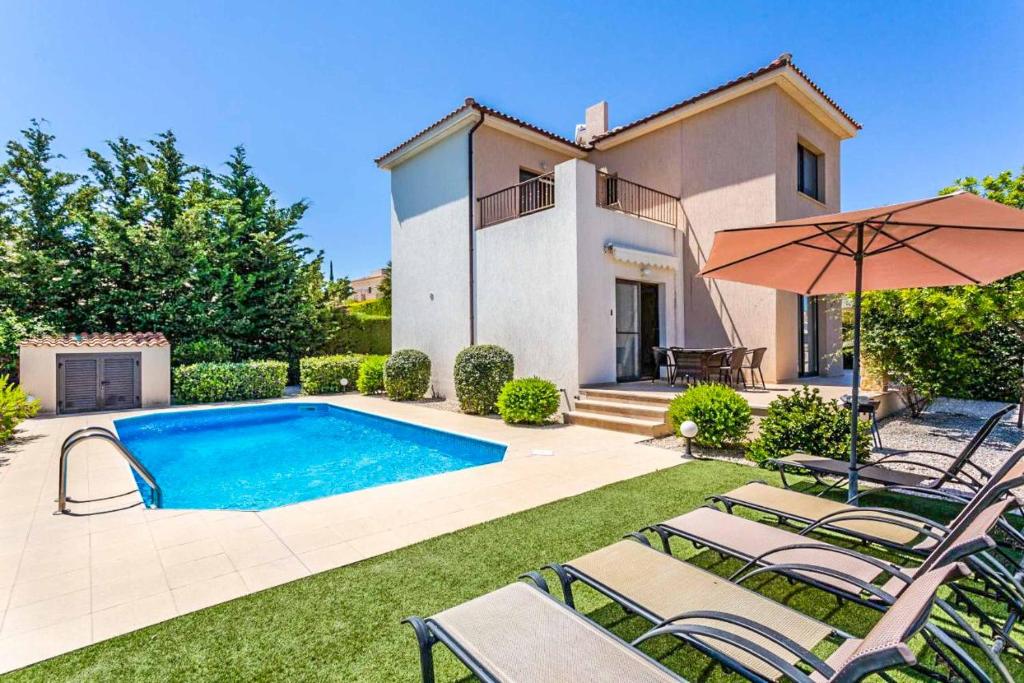 een villa met een zwembad, 2 ligstoelen en een parasol bij Villa Lara Latchi in Lachi