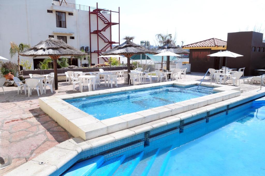 una piscina con sillas, mesa y sombrilla en Hotel Presidente en Villa Carlos Paz