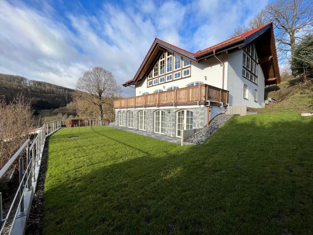 a large white house on a hill with a green yard at Ferienwohnung Blick Thyratal in Stolberg