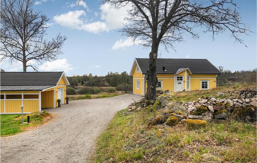 a house on a dirt road next to a tree at Awesome Home In Ronneby With Kitchen in Ronneby