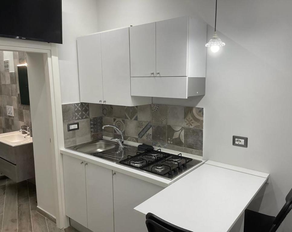 a white kitchen with a stove and a sink at La Casina di Michele a Napoli in Naples