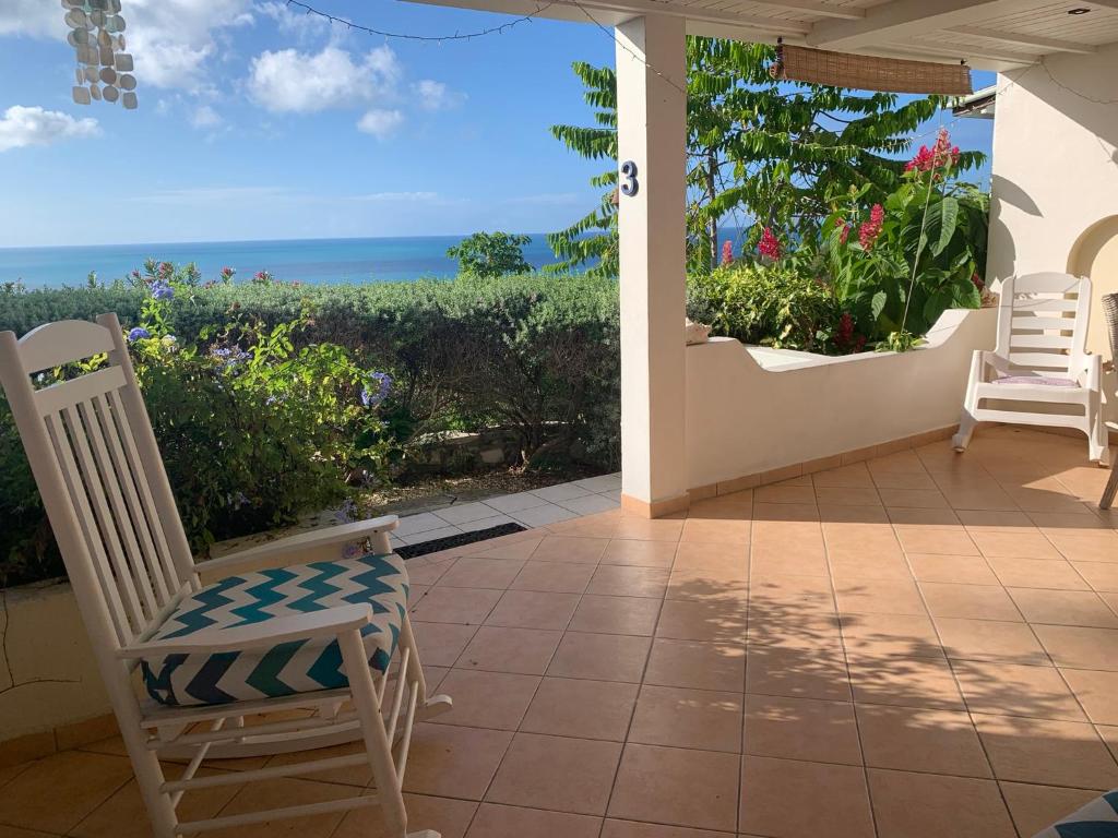 a porch with chairs and a view of the ocean at Vista Mare in Dickenson Bay