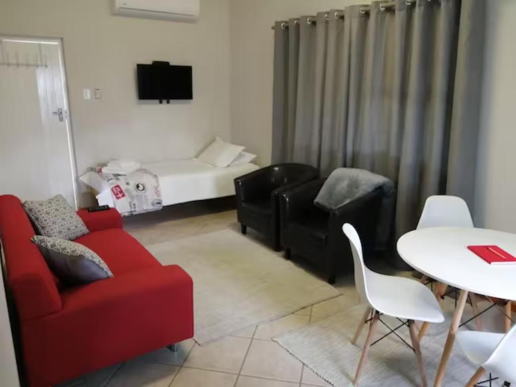 a living room with a red couch and a table at A Touch of Red in Oudtshoorn