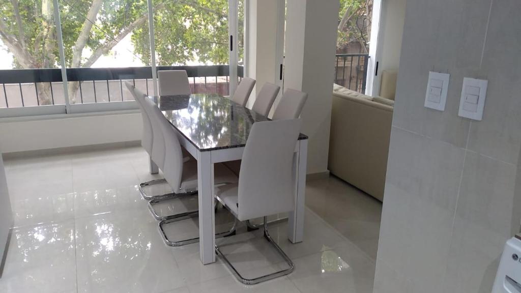 comedor con mesa de cristal y sillas blancas en Amplio departamento Balcon pleno centro Peatonal en Mendoza