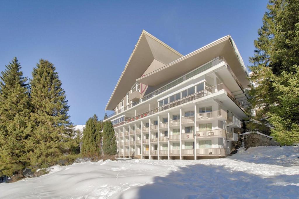 un grand bâtiment dans la neige avec des arbres dans l'établissement Belambra Clubs Gourette - Lou Sarri, à Gourette