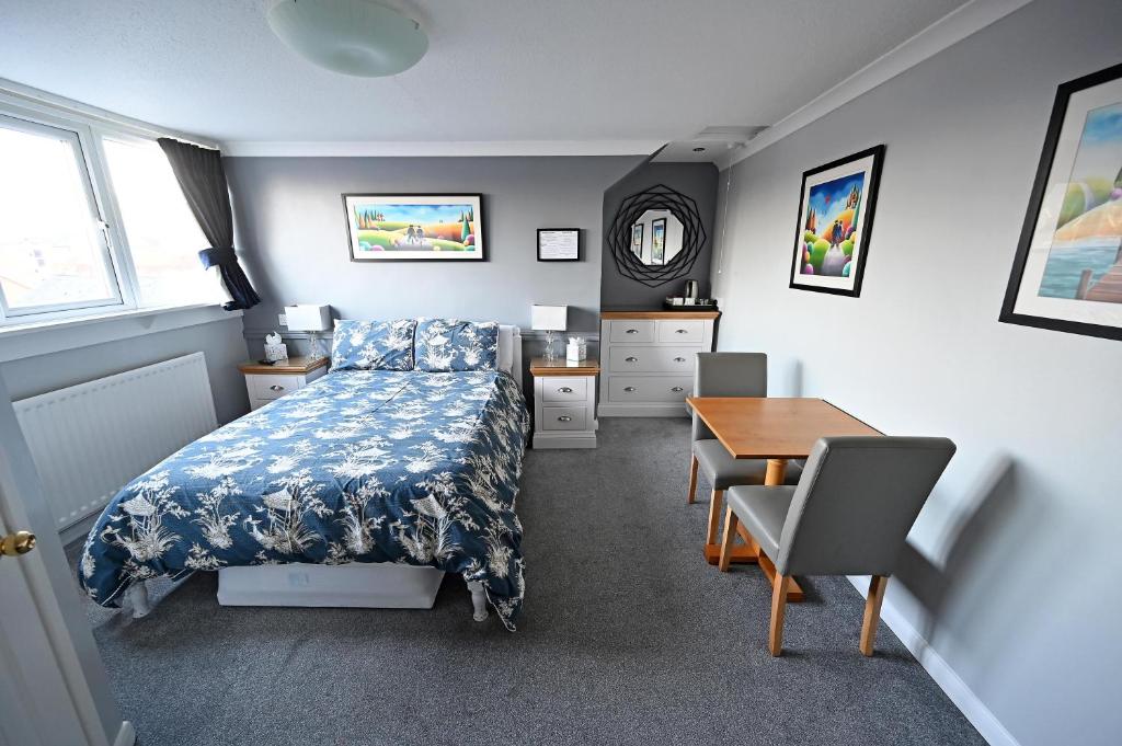 um quarto com uma cama, uma secretária e uma mesa em Avoncot Guest House em Stratford-upon-Avon