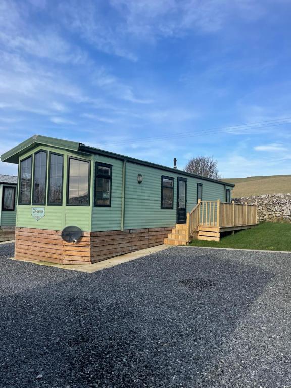 a green caravan with a deck and a house at Immaculate 2-Bed Static Caravan at Monrieth in Newton Stewart
