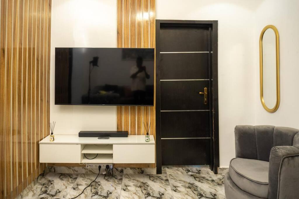 a living room with a desk and a tv and a chair at Awesome 1-Bed-Apt With 24hrs Power & Fast WiFi in Lagos