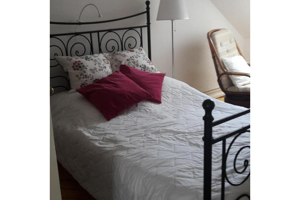 een zwart bed met witte lakens en rode kussens bij Private Room in Hannover