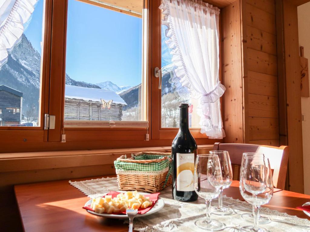 オーデールにあるApartment Chalet Molignon by Interhomeのワイングラス付きのテーブルに座ったワイン1本