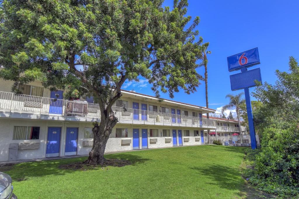 a building with a tree in front of a building at Motel 6-Chino, CA - Los Angeles Area in Chino