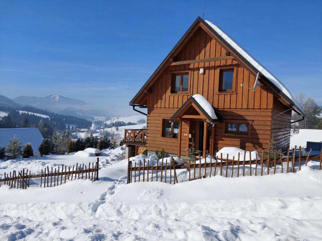 eine Holzhütte im Schnee mit einem Zaun in der Unterkunft Drevenica Huty in Huty